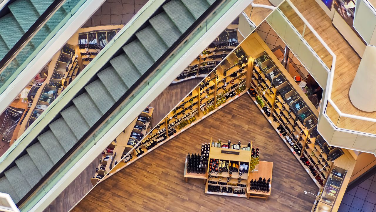 Aerial view of a bright airport retail gallery with escalators and shelf displays